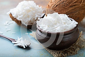 Coconut flakes in a clay bowl on a blue background