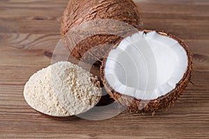 Coconut flour in a bowl on brown wooden background