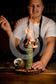 coconut and glass with alcoholic cocktail on a bar counter Fire and sparks over a glass.