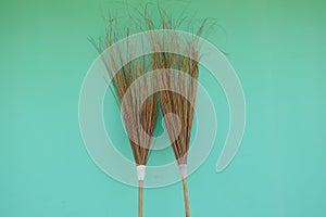 Coconut leaf broom on green background.