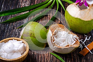 The coconut meats is in a coconut shell and a wooden bowl. Decorated with coconut water, ready to serve on a wooden table