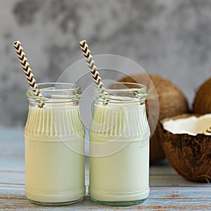 Coconut milk and coconuts on a light background