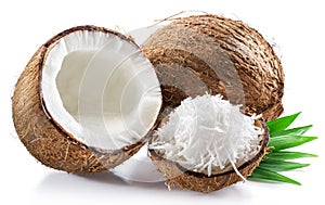 Coconut milk in cracked coconut fruit and coconut shreds on white background