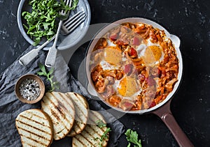 Coconut milk curry vegetables shakshuka and grilled bread on dark background, top view