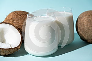 Coconut milk in a glasses among coconuts on a blue background