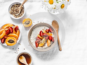 Coconut milk oatmeal porridge with strawberries, apricots, honey and flax seeds. Delicious healthy breakfast on a light background
