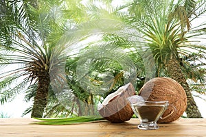 Coconut and natural organic oil on table against tropical palm trees