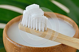 Coconut oil in a bowl with a wooden toothbrush - Homemade whitening toothpaste