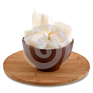 Coconut oil in brown bowl on wood board isolated on white background, copy space.