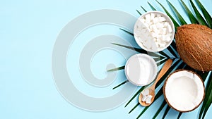 Coconut oil cosmetic cream and palm leaf on blue background top view. Skin care, body and hair treatment concept