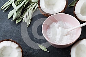 Coconut oil with fresh coconuts fruit on black stone background. Natural and organic beauty cosmetic.