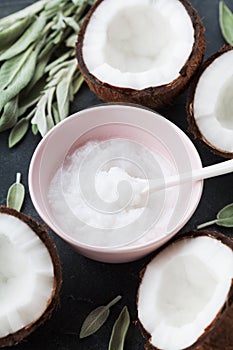 Coconut oil with fresh coconuts fruit on black stone table. Natural organic cosmetic for body care and beauty.