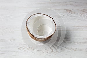 Coconut open in half seen from above with light wooden background