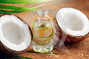 Coconut palm oil in a bottle with coconuts and green palm tree leaf on brown background. Coco nut closeup. Healthy food, skincare