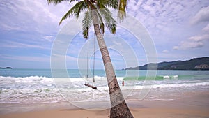 Coconut palm trees with tropical paradise beautiful beach and wave crashing on sandy shore at Patong beach Phuket Thailand.