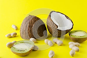 Coconut, peanuts, kiwi fruit on yellow brigh surface -concept of traveling, vacation at the exotic countries