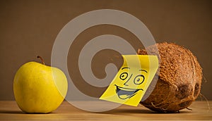 Coconut with post-it note smiling at apple