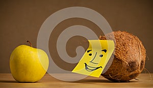 Coconut with post-it note smiling at apple