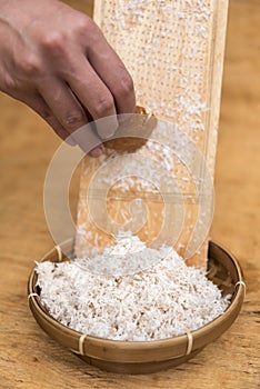 Coconut pulp grated on wooden shredder