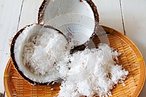 Coconut shell and Freshly grated coconut on bamboo tray