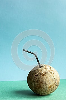 Coconut with a straw on a green-blue background with place for text.