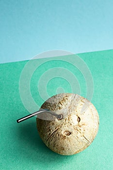 Coconut with a straw on a green-blue background with place for text.