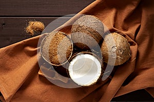 Coconut sugar, in a bowl of coconut, on a wooden brown background, top view,