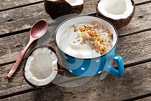 Coconut yogurt with granola in cup on wooden table. Probiotic food concept Tasty and healthy breakfast photo