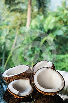 Coconuts on the black glass table isolated over blurred palm trees background