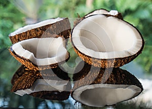 Coconuts on the black glass table isolated over blurred palm trees background