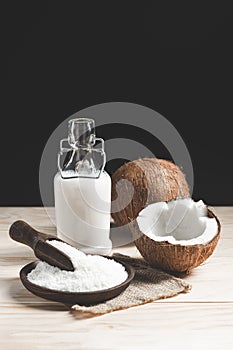 Composition with coconuts, coconut milk and grated coconut on dark background