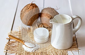 Coconuts and coconut milk in a metal pot. Wooden background