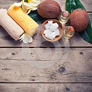 Coconuts, coconut oil and towels on vintage wooden background.