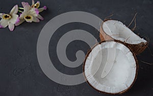 Coconuts with mint and orhid flowers, on dark background. Copy space.
