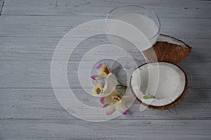 Coconuts with mint and orhid flowers, on dark background. Copy space.