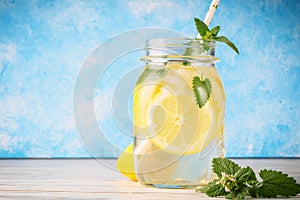 Coctail jar of lemonade and mint leaves on wooden table blue background