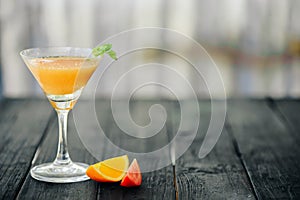 Coctail with orange and tomato on black wooden table at blurred background