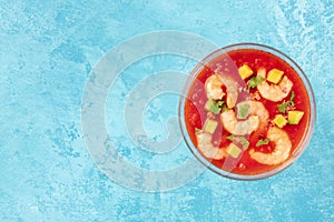 Coctel de camarones, Mexican shrimp cocktail with avocado, a top-down shot on a blue background with a place for text photo