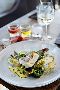 Cod fillet with cauliflower cream, asparagus, clam-wine sauce and mussles. Delicious seafood fish closeup served on a