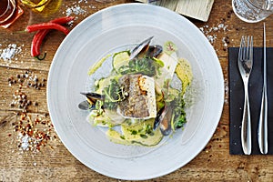 Cod fillet with cauliflower cream, asparagus, clam-wine sauce and mussles. Delicious seafood fish closeup served on a