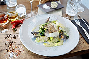 Cod fillet with cauliflower cream, asparagus, clam-wine sauce and mussles. Delicious seafood fish closeup served on a