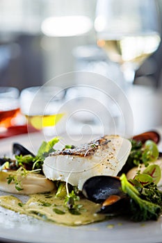 Cod fillet with cauliflower cream, asparagus, clam-wine sauce and mussles. Delicious seafood fish closeup served on a