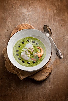 Cod fillet and shrimp over zucchini cream on wood background