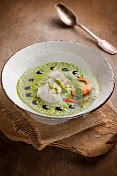 Cod fillet and shrimp over zucchini cream on wood background