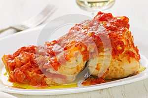 Cod fish with tomato sauce on white dish
