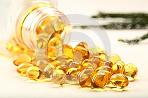 Cod liver oil capsules falling from glass bottle  on white background.