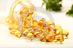 Cod liver oil capsules falling from glass bottle  on white background.