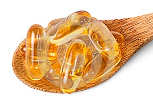 Cod liver oil omega 3 capsules on wooden spoon