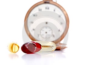 Cod liver oil omega 3 gel capsules in front of vintage pocket clock