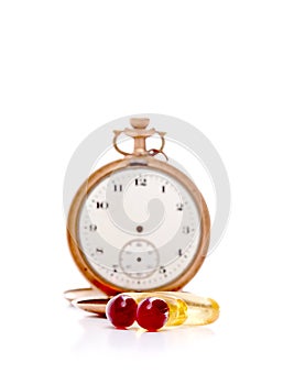 Cod liver oil omega 3 gel capsules in front of vintage pocket clock